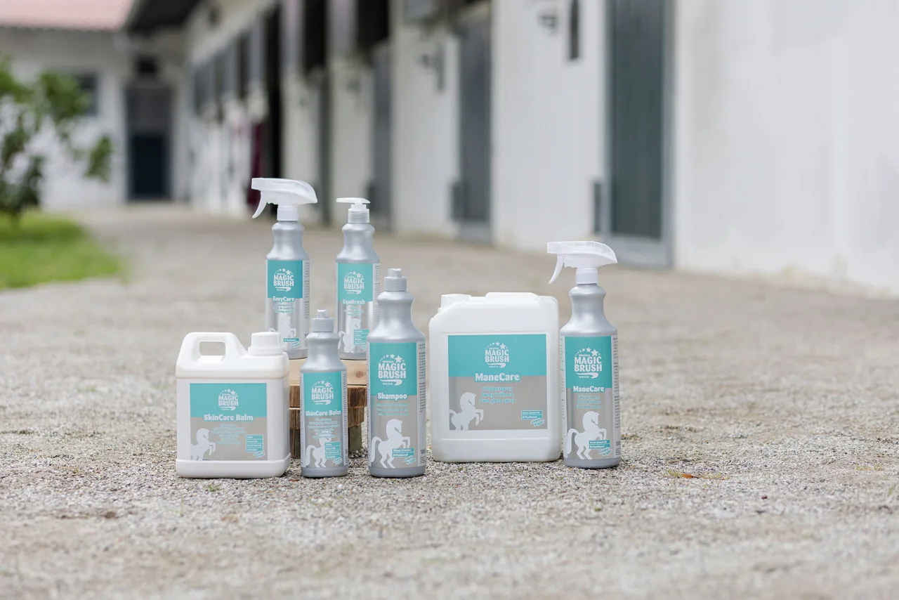 Produktgruppe der Magic-Brush-Pflegeserie, mehrere Flaschen und Kanister auf dem Stallweg
