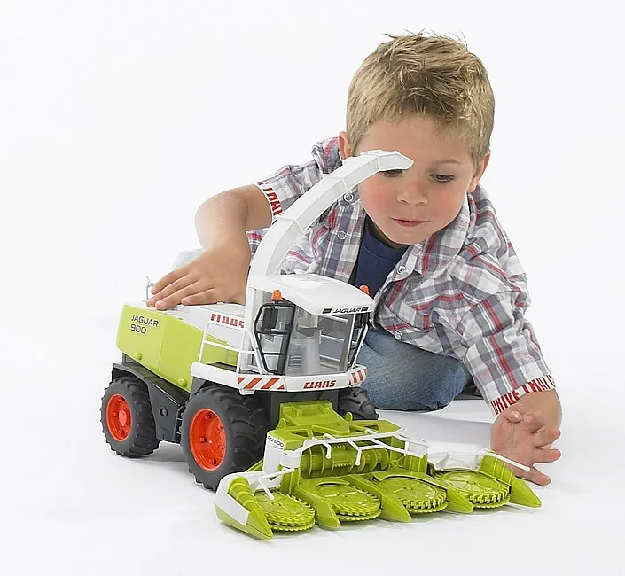 Kind spielt auf dem Boden mit dem Claas Jaguar 900 Maishäcksler von Bruder