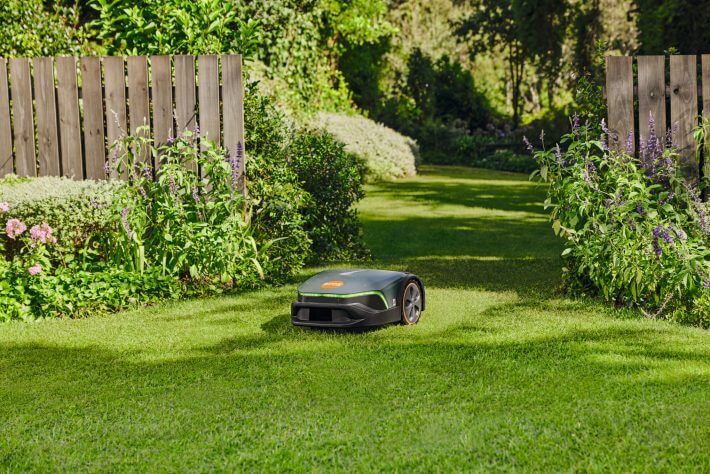 STIHL iMOW 7 EVO Mähroboter im Garten mit blühenden Beeten