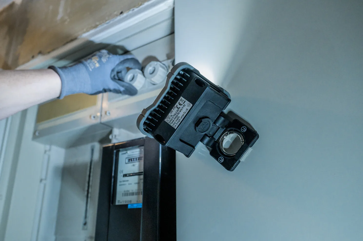 Montage eines grauen LED-Strahlers mit Bewegungsmelder an der Wand