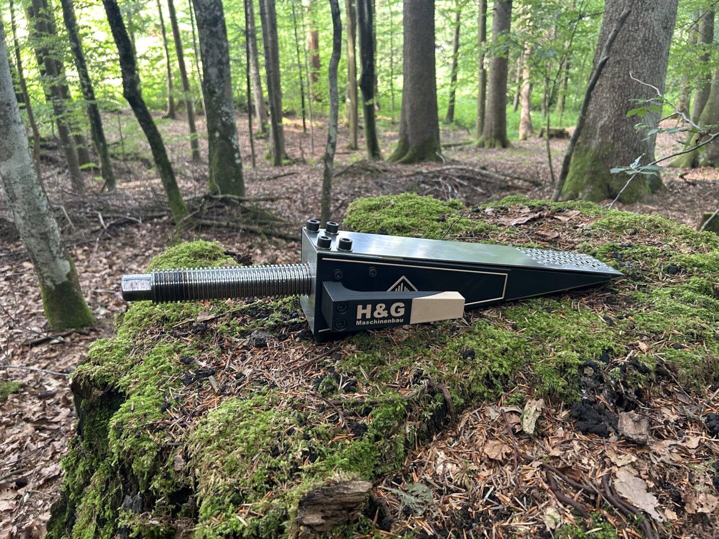 Robuster H&G Spindelkeil X9036 bereit zum Einsatz auf einem Baumstumpf im Wald