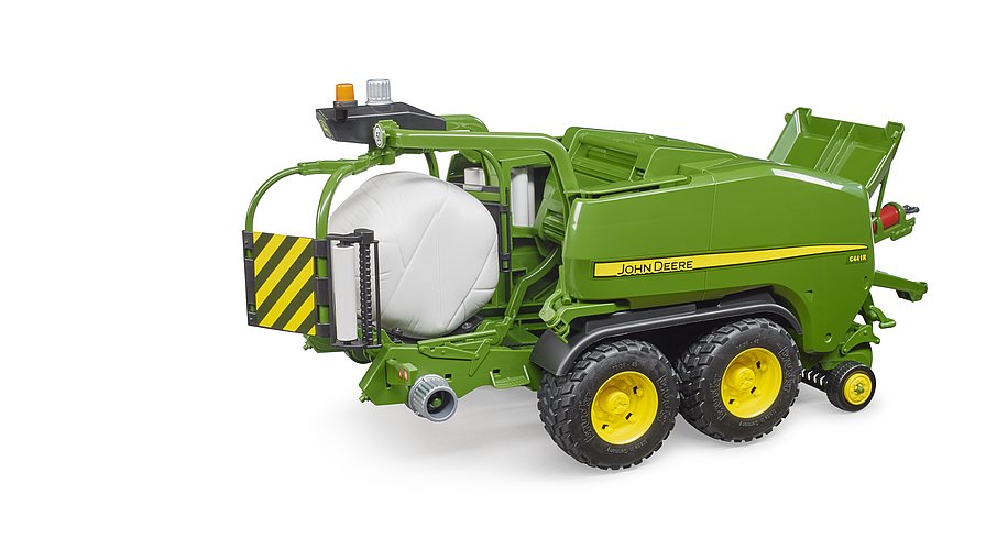 John Deere C441R auf dem Wickeltisch mit weißem foliertem Rundballen
