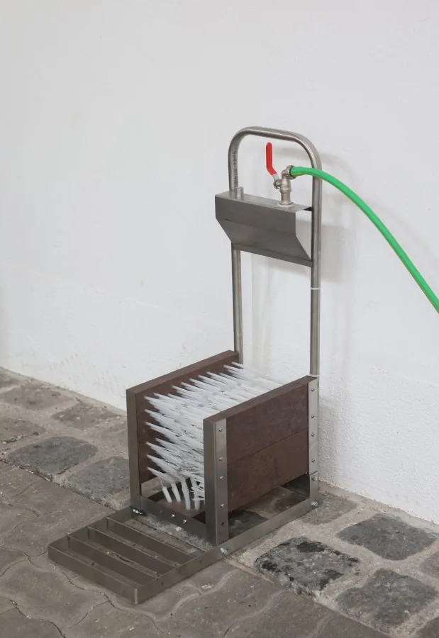 Edelstahl-Stiefelreiniger mit Wasserschlauch an der Wand