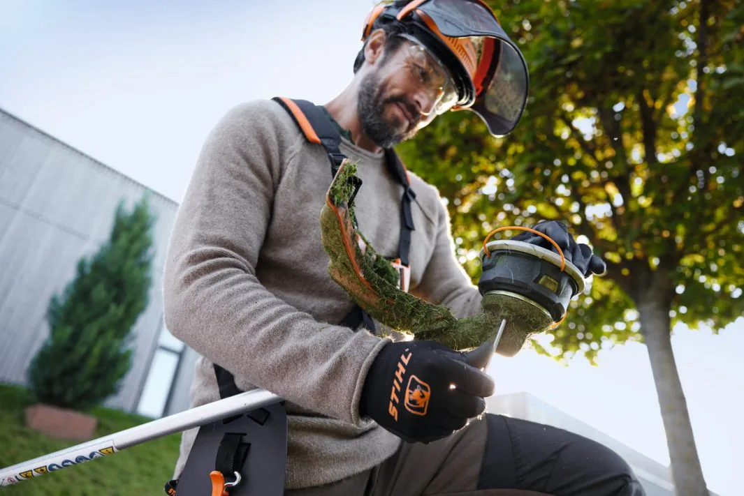 Mann prüft den Mähkopf der STIHL FSA 120 Akku-Motorsense