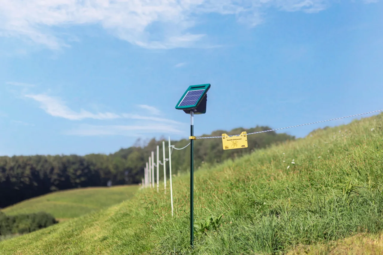 SunPower S1000 Solargerät auf Erdstab am Weidezaun, Hügellandschaft