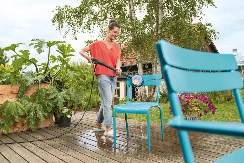 Frau reinigt einen blauen Gartenstuhl mit der Kärcher WB 130 Waschbürste
