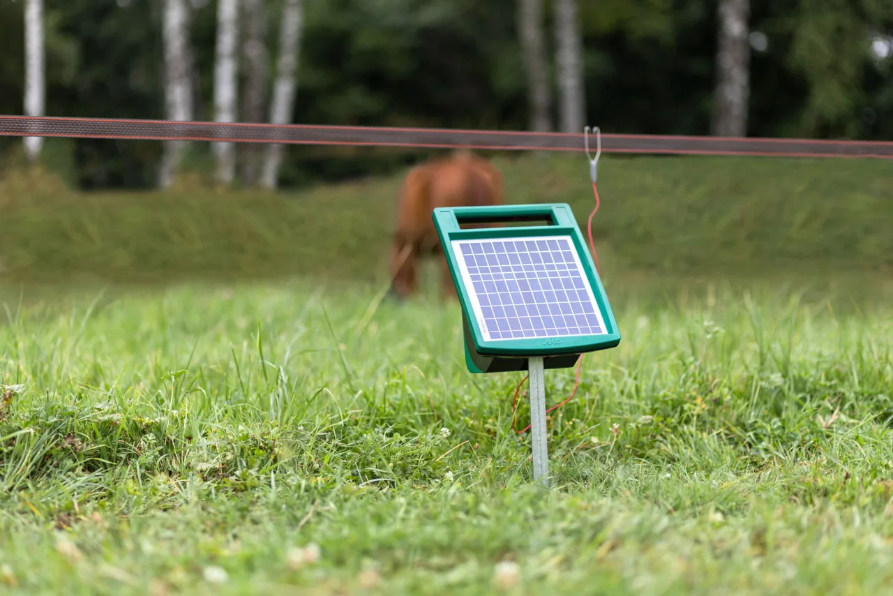 SunPower S1000 Solargerät auf Erdstab am Weidezaun, Pferd dahinter