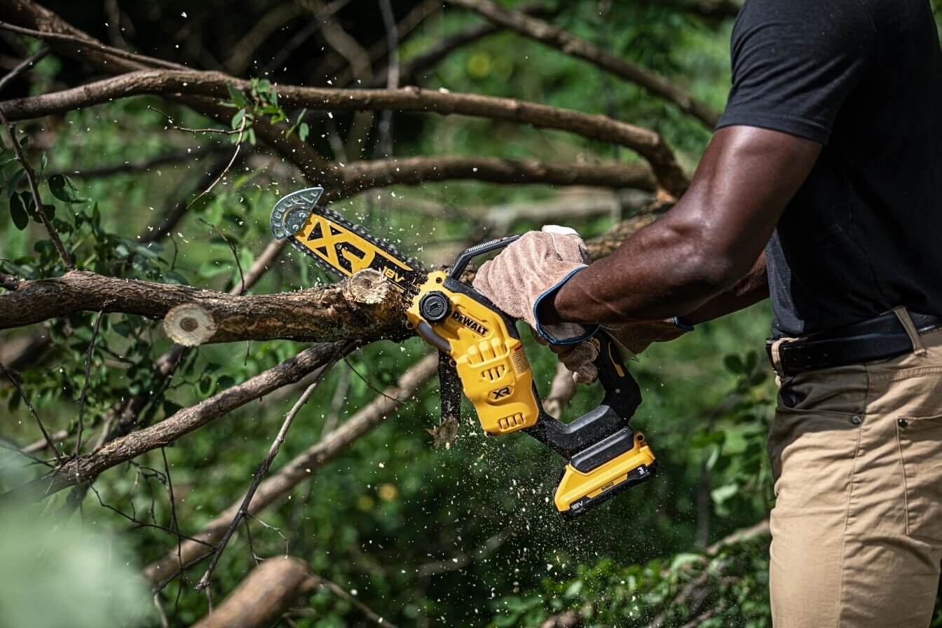Mann schneidet mit der DeWalt DCMPS520N Akku-Ast-Kettensäge einen Ast
