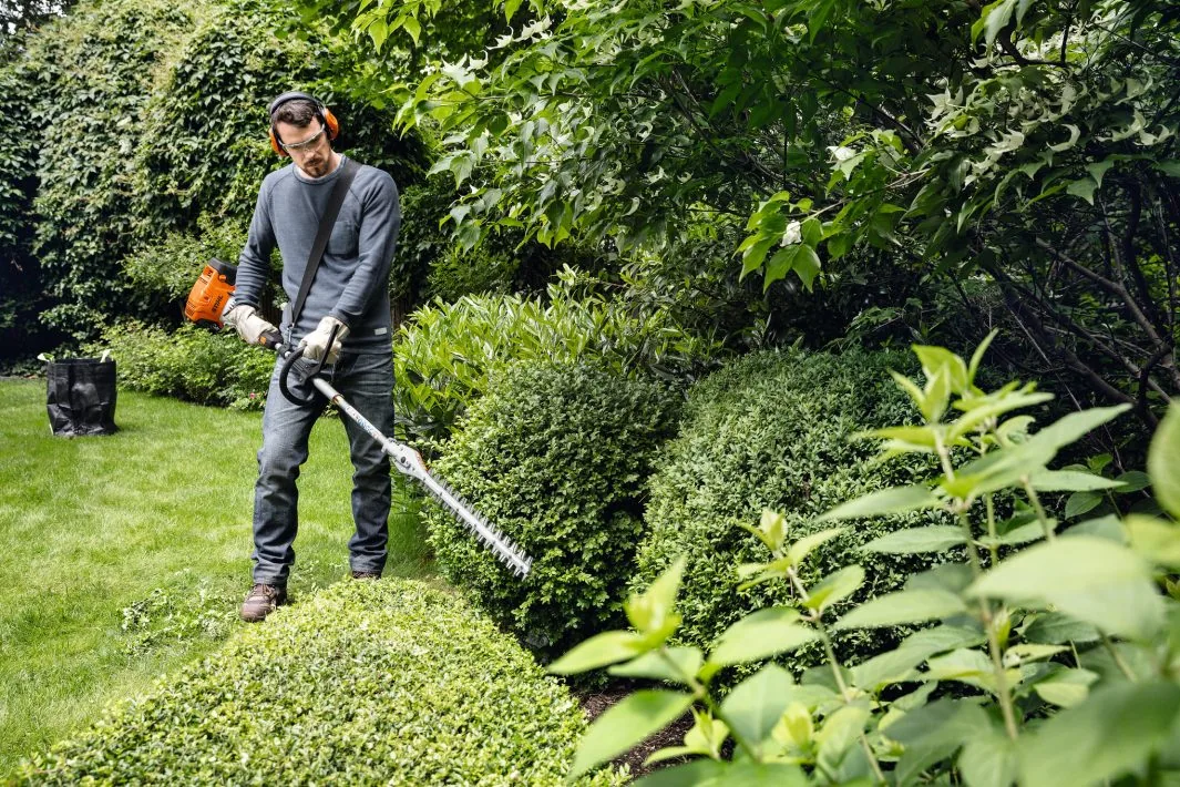 STIHL HL-KM 0° Heckenschneider-Aufsatz für das KombiSystem im Einsatz an einer niedrigen Hecke