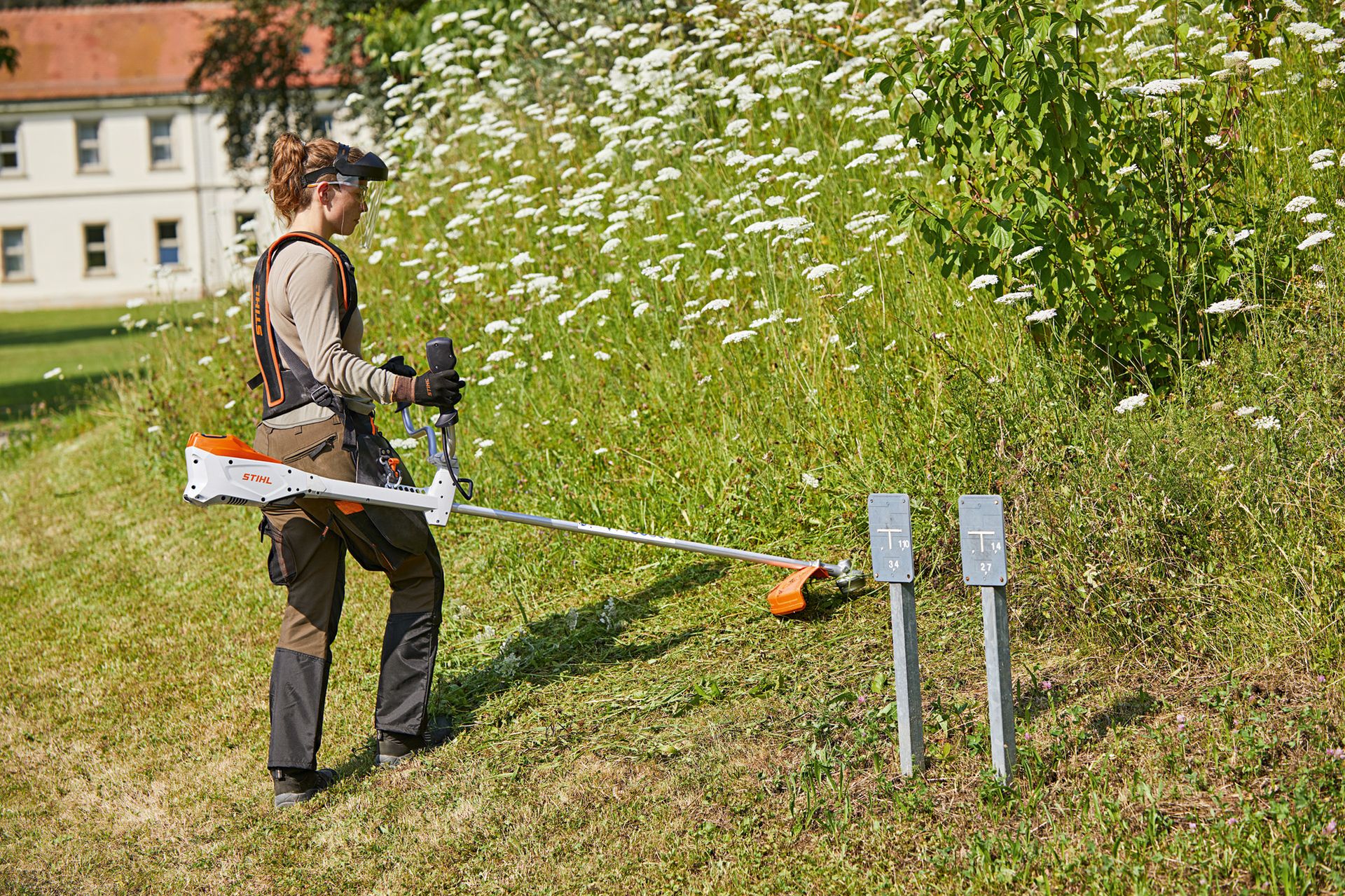 Frau mäht mit der STIHL FSA 135 Akku-Motorsense eine Böschung