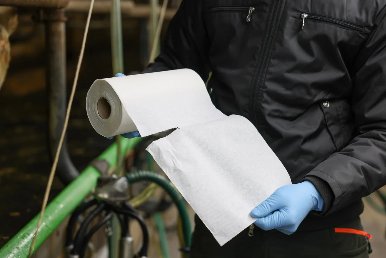 Person hält eine Rolle Kerbl UdderoClean Euterpapier im Stall