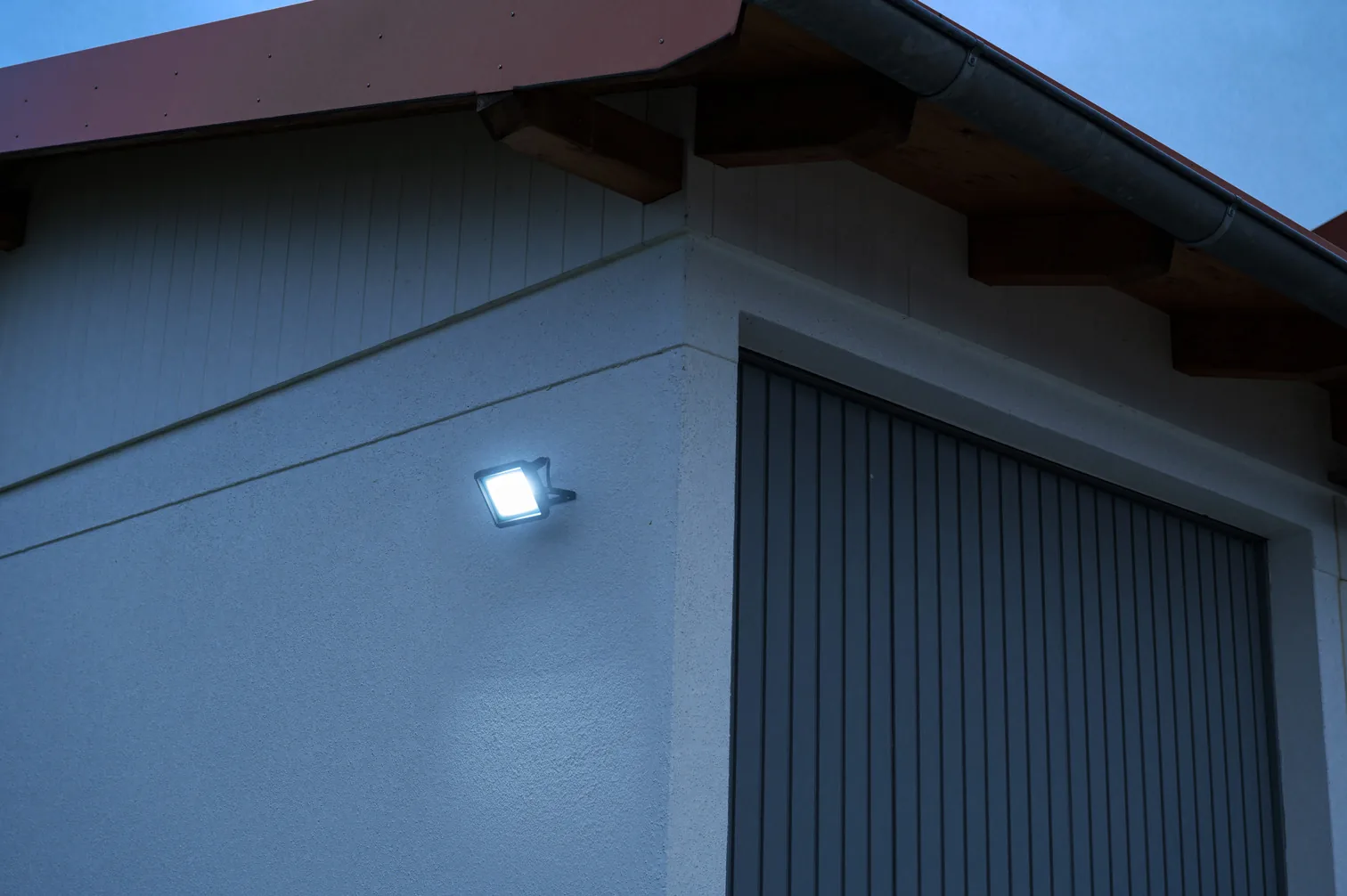 Brennenstuhl LED Strahler JARO 4060 Wandmontage am Giebel eines Gartenhauses bei Dämmerung