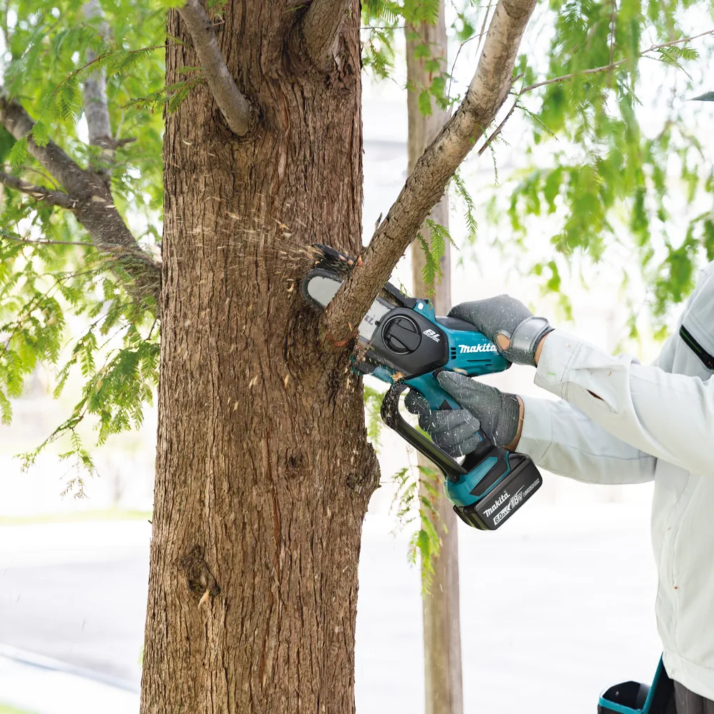 Makita Akku-Astsäge beim Schneiden eines Astes am Baum