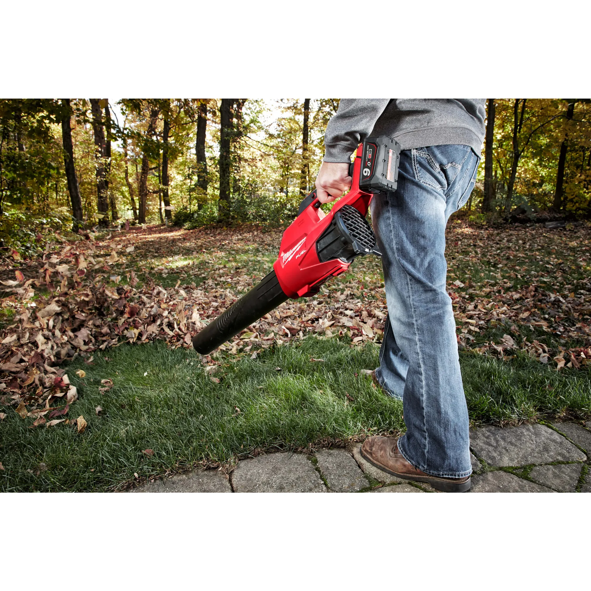 Mann bläst mit dem Milwaukee M18 FBL-0 Herbstlaub vom Rasen