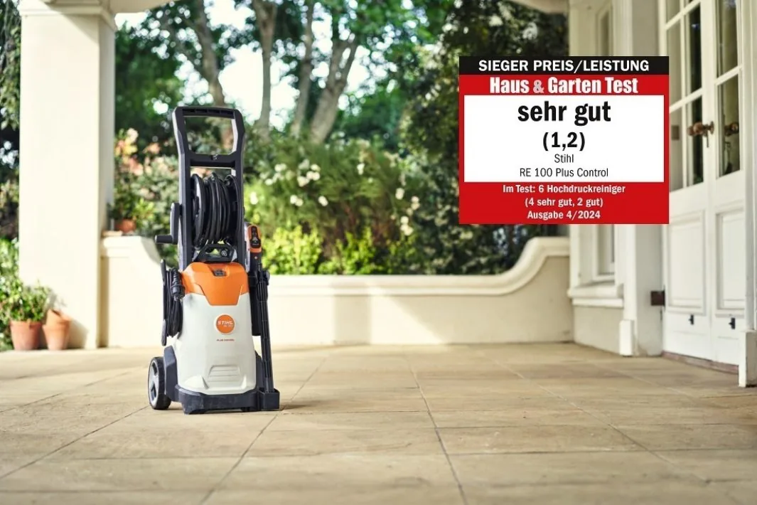 STIHL RE 100 PLUS Control Hochdruckreiniger vor einem Haus mit Test-Siegel „sehr gut“