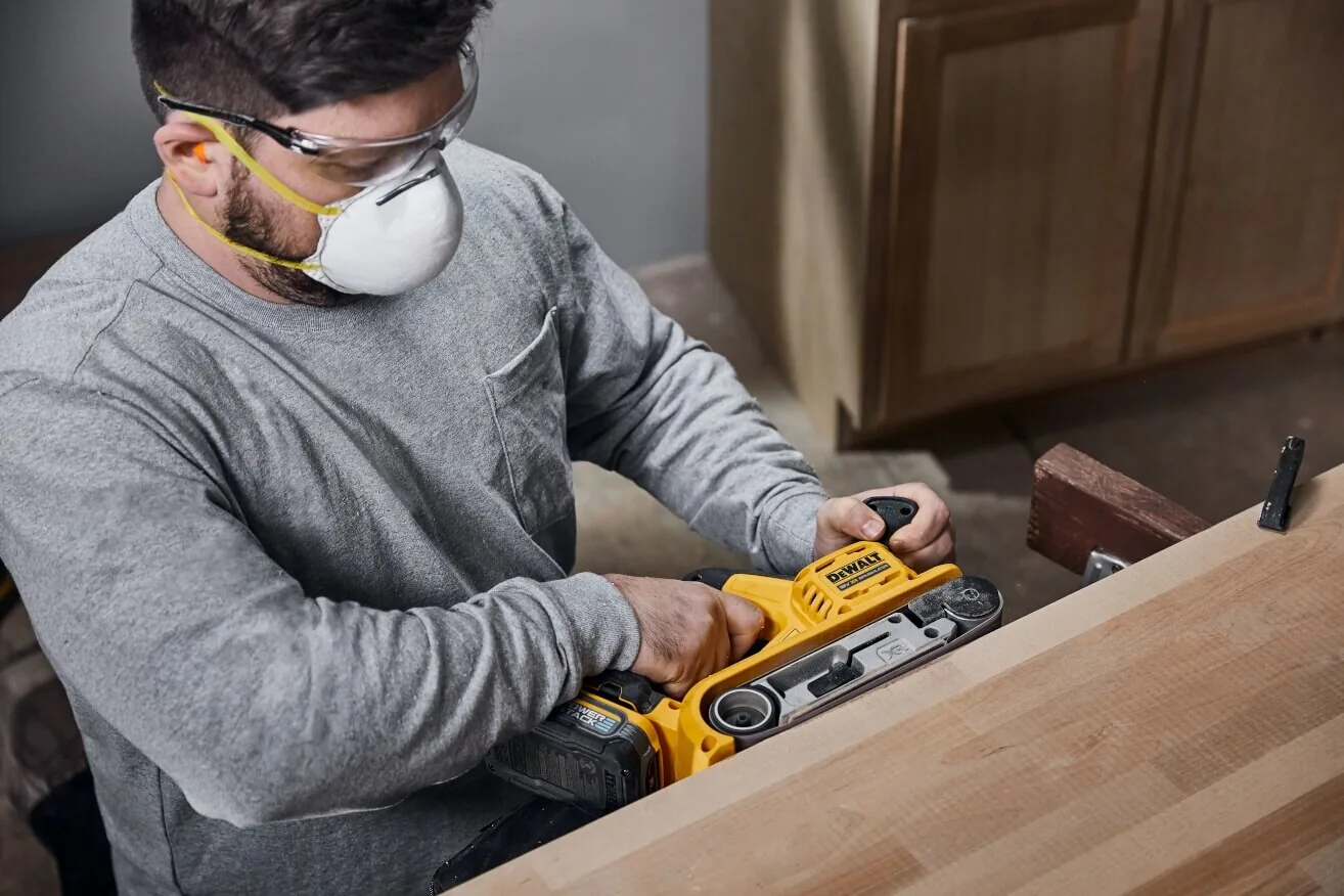 DeWalt DCW220NT Akku-Bandschleifer im Einsatz an einem Schrank (Maske)