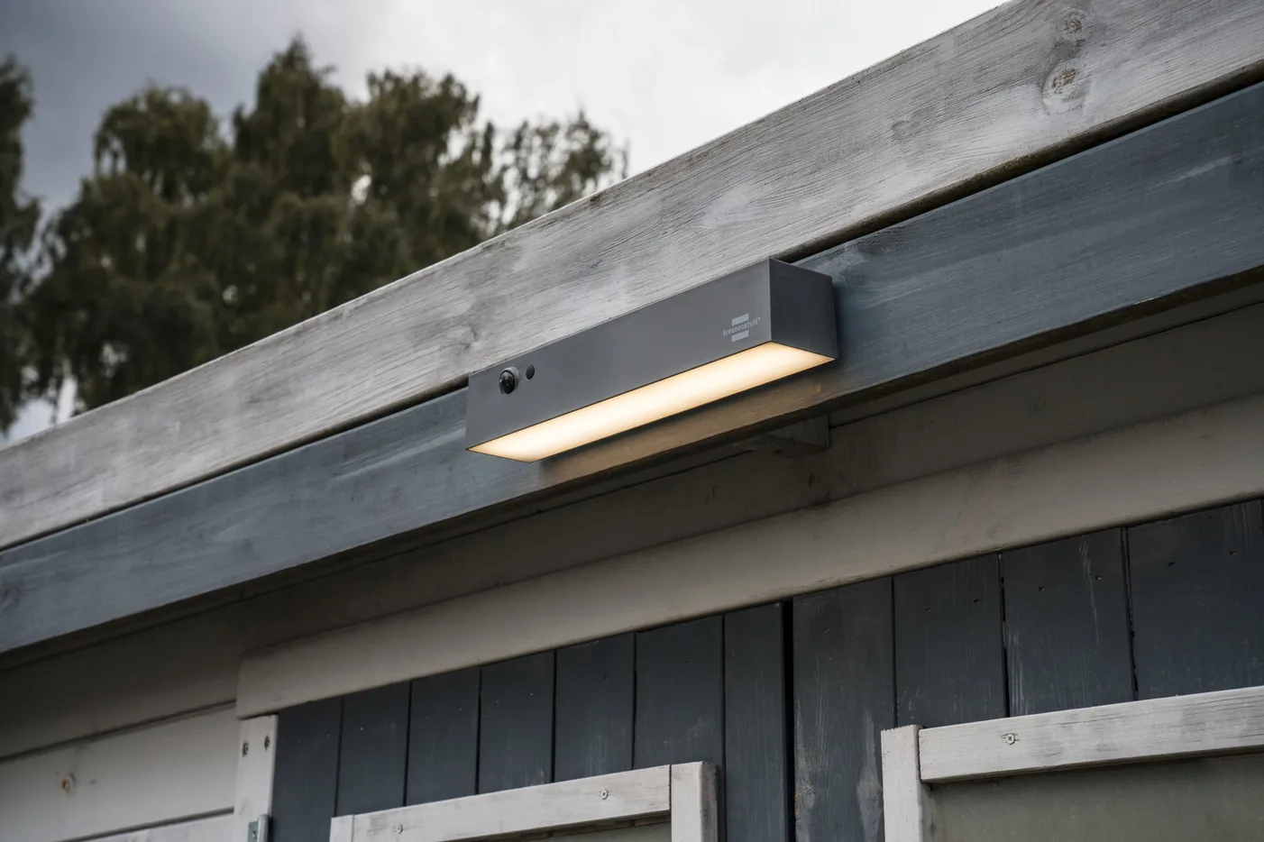 Brennenstuhl Solar LED Strahler SOL 1000 Cubus an einem Gartenhaus, warmweiß leuchtend