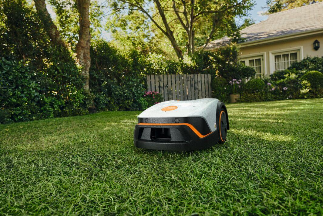 STIHL iMOW 4 Mähroboter im Garten vor einem Haus