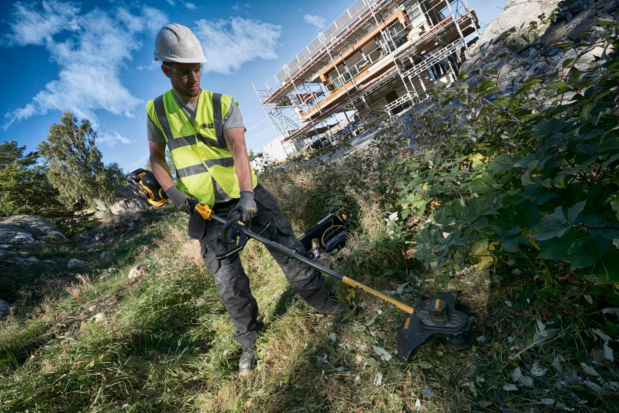 DeWalt DCM571N FLEXVOLT Rasentrimmer im Einsatz beim Mähen einer Böschung