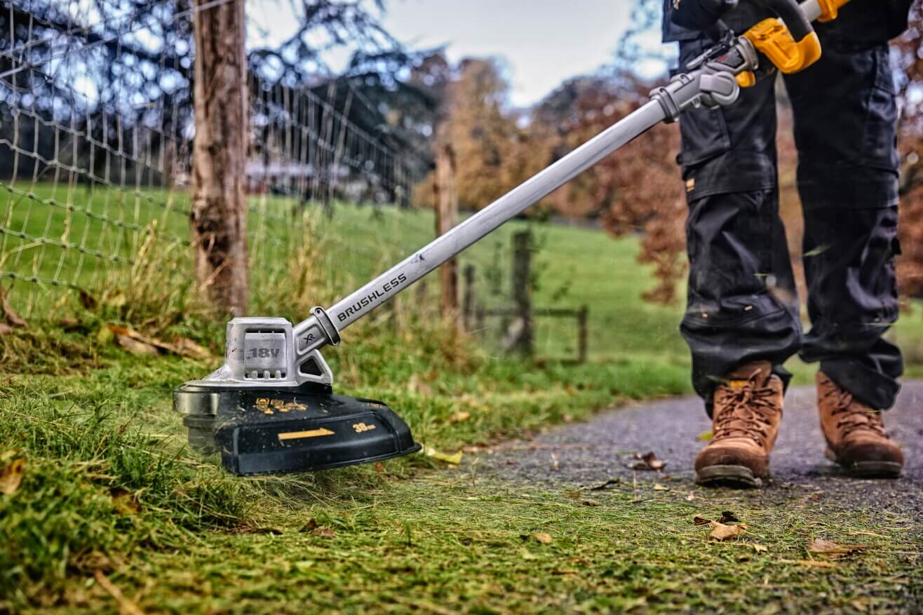 DeWalt DCMST561N 18V XR Akku-Rasentrimmer im Einsatz beim Kantentrimmen am Weg