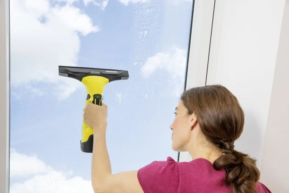 Frau reinigt ein Fenster mit dem Kärcher WV 5 Plus N Fenstersauger