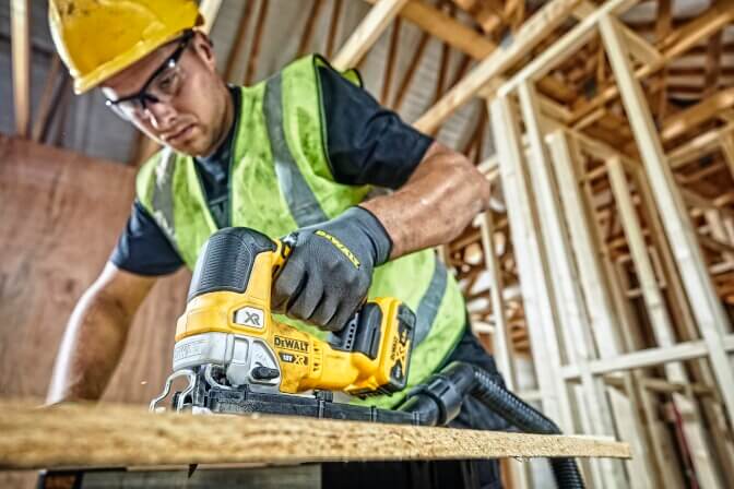 Mann sägt mit der DeWalt DCS334NT Akku-Stichsäge Holz auf der Baustelle