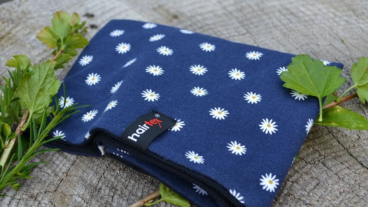 Blauer Hairtex Stall-Beanie mit Edelweiß-Muster auf Holz, mit Pflanzen