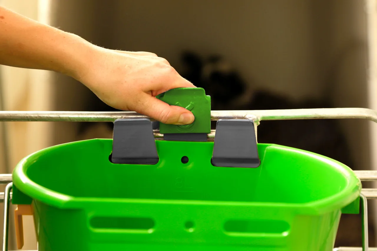 Hand setzt einen grünen Kerbl Eimer mit Bucket-Guard-Halter ein