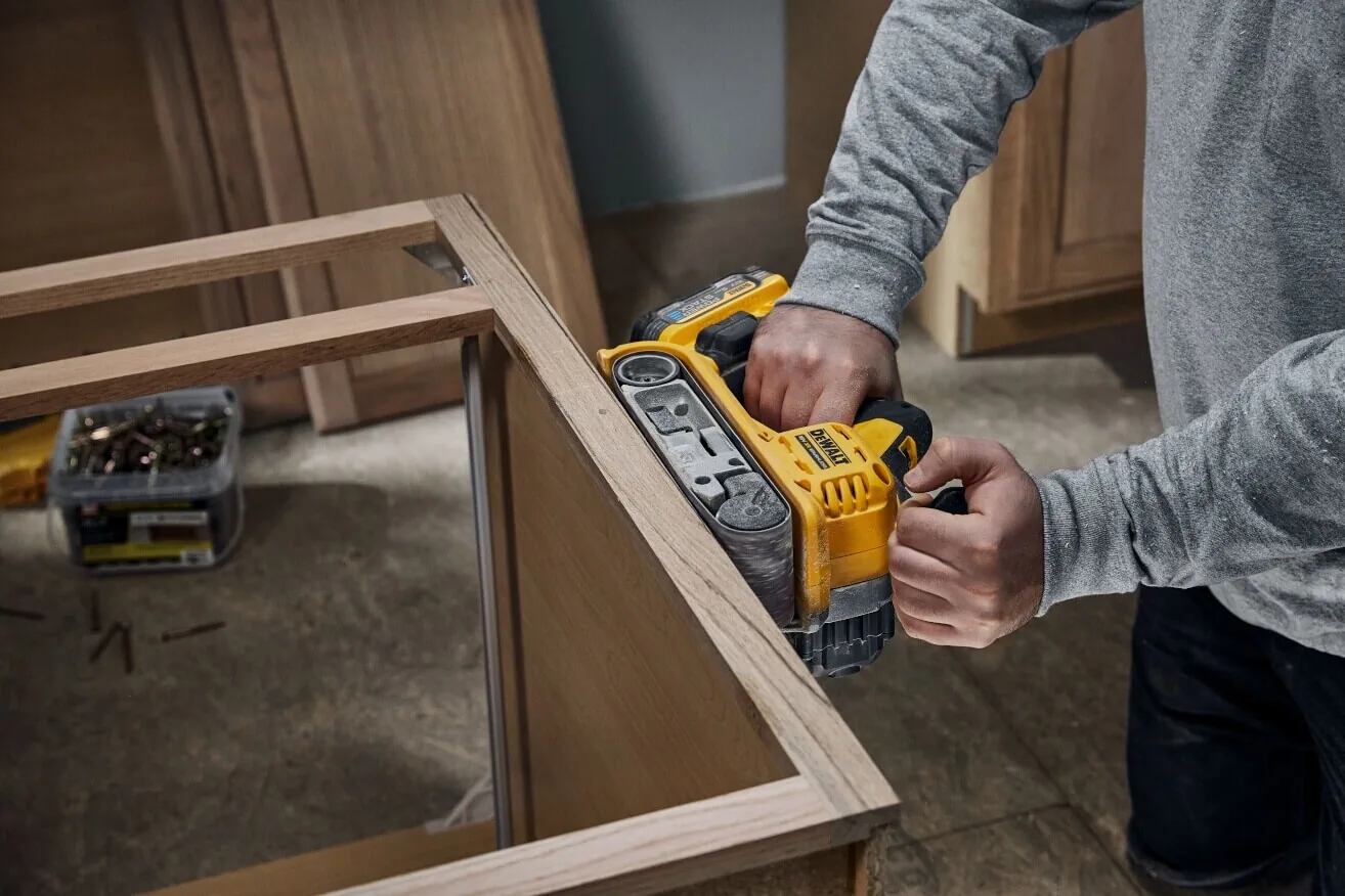 DeWalt DCW220NT Akku-Bandschleifer im Einsatz am Schrank, Detailansicht