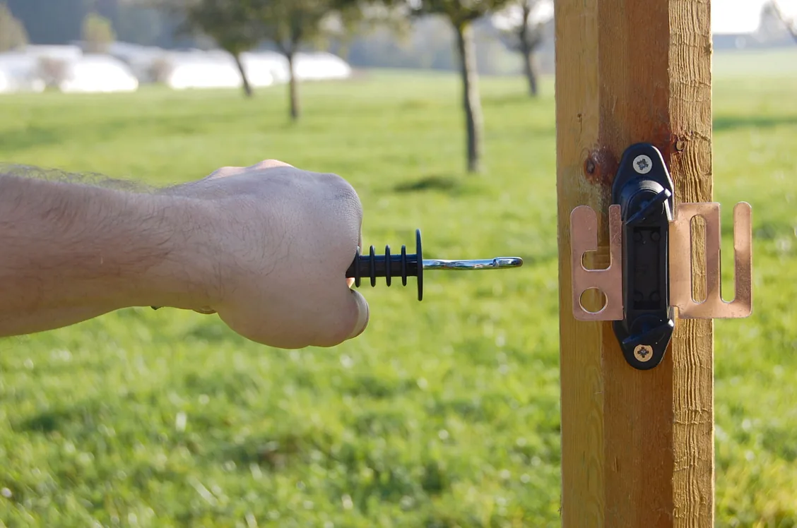 Hand löst den Torgriff aus dem roten FLEXIGATE-Halter am Pfosten, Detail
