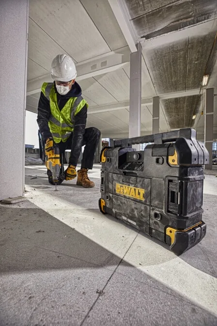 Mann hebt das DeWalt DWST1-81078 TSTAK Baustellenradio auf der Baustelle
