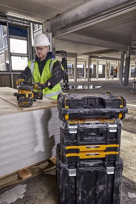 Mann trägt das DeWalt DWST1-81078 TSTAK Baustellenradio auf der Baustelle