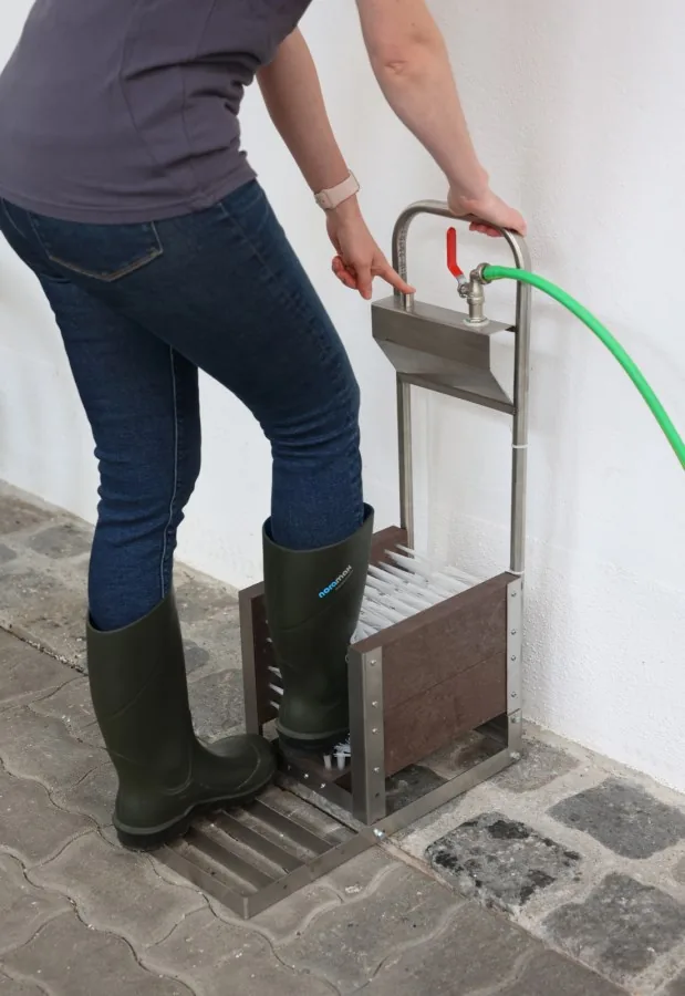 Person reinigt die Stiefel am Stiefelreiniger von hinten